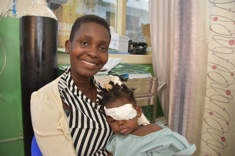 Una madre sorride, tenendo in braccio il suo bambino con una benda sull'occhio, mostrando l'impatto positivo di piccole donazioni